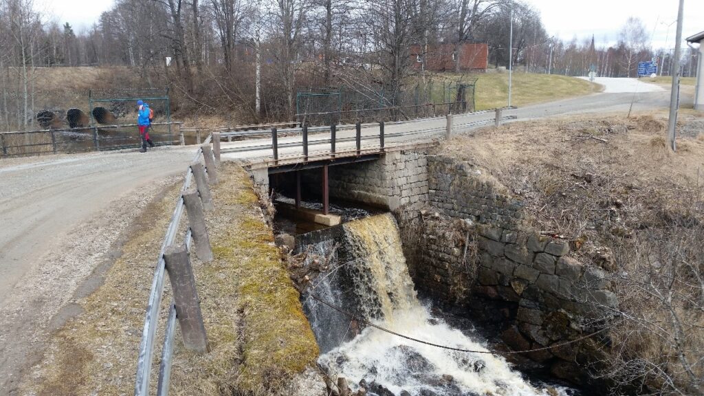 Väg över en fördämning, på bron står en person i blå jacka