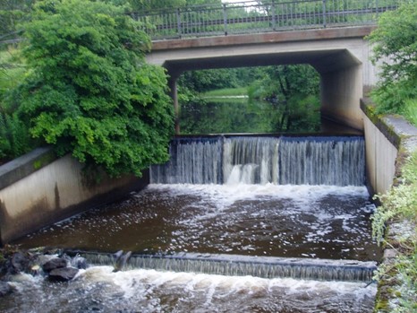 Bro över uppdämt vattendrag med fall
