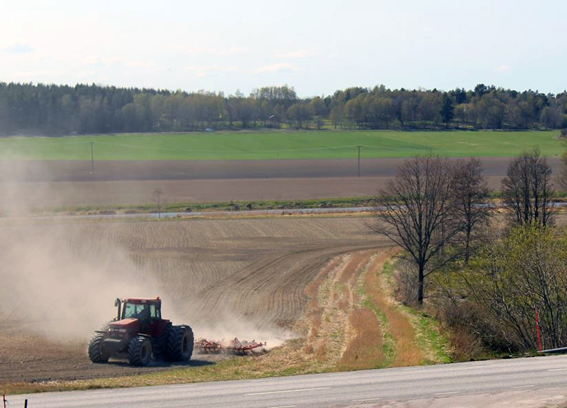En traktor som plöjer på en åker en vårdag.