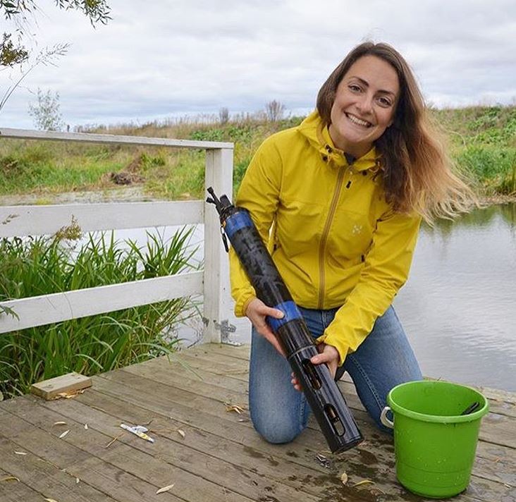 Kvinna i gul jacka som håller i ett rörliknande föremål