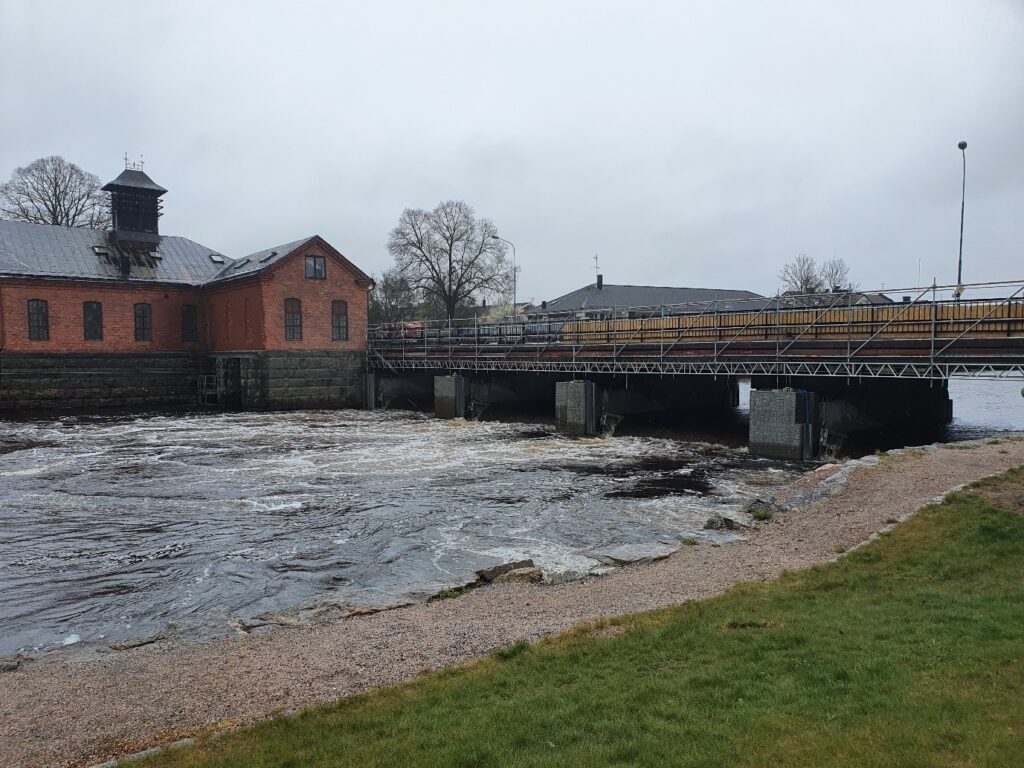 Dammen vid Herrgårdsbron i Arboga sedd nedströms ifrån. Den tidigare kraftverksbyggnaden och fiskvägens utlopp syns till vänster i bild.