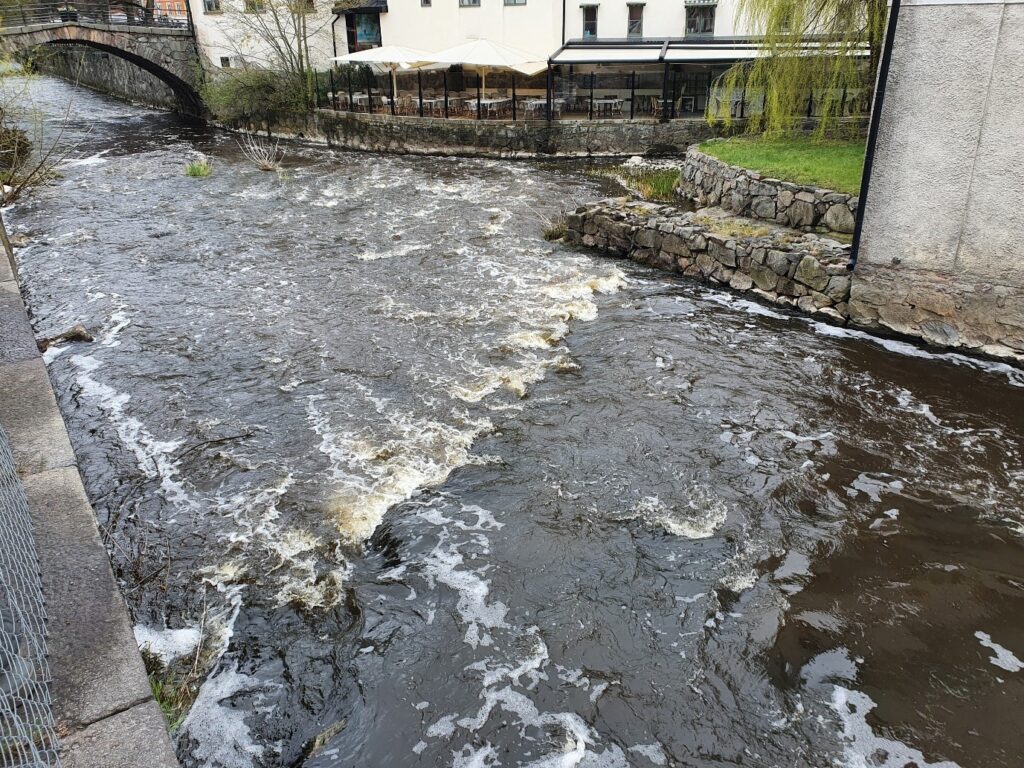 Strömsträckan/forsen nedströms Kvarnfallet i Uppsala. En stensatt ränna nedströms det vänstra utskovet under kvarnbyggnaden till höger i bild.