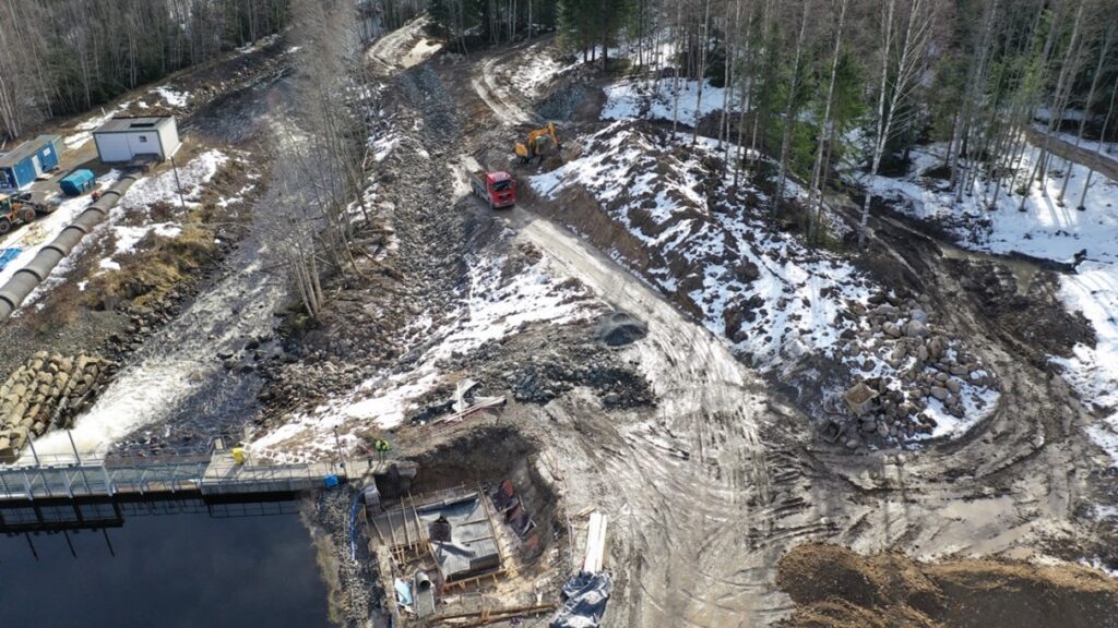 Foto över byggarbetsplats med leriga vägar och snö på marken.