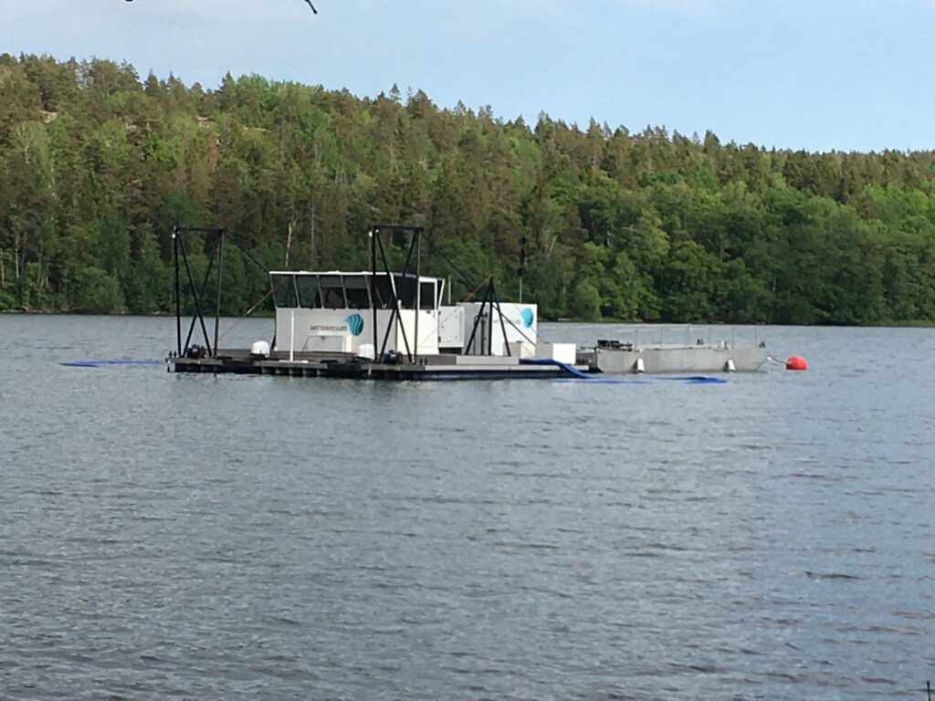 Pråm i mitten av sjö med skog i bakgrunden