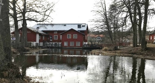 En röd byggnad med vattenspegel i förgrunden