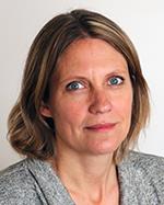 Kvinna med brunt hår ned till axlarna, blå ögon och en grå tröja.
