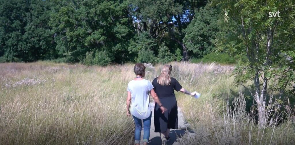 Två kvinnor går över ängsliknande område där vattenparken ska anläggas.